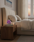 Purple faceted crystal night lamp glowing on a wooden nightstand in a warm bedroom
