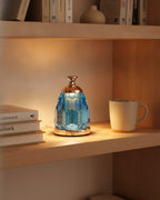 Blue crystal night lamp on a wooden bookshelf between books